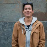 A smiling man leaning in front of the wall
